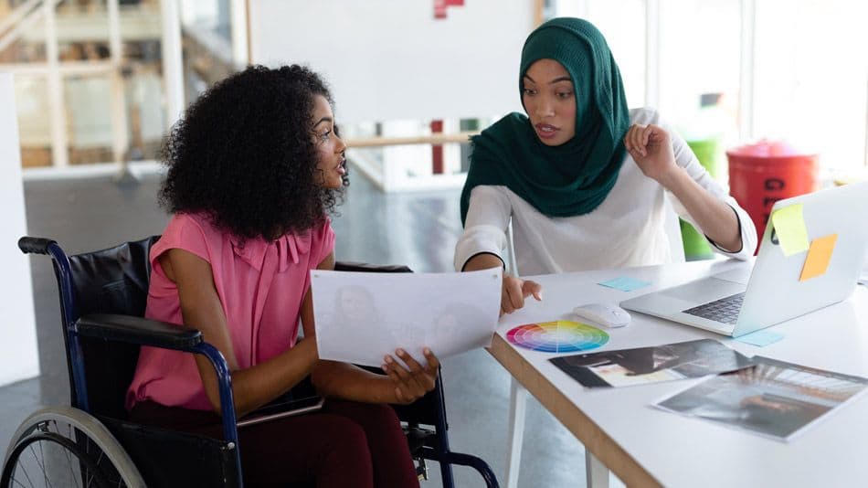 Two people discussing papers at a desk