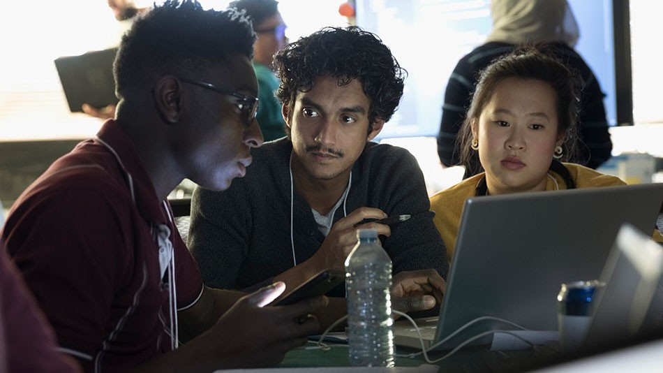 Pessoas reunidas em torno de um notebook enquanto conversam